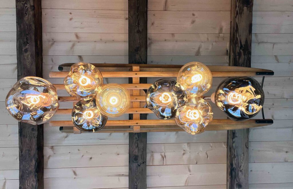 Luminaire sur mesure Il-Umine : luge en bois suspendue avec ampoules en verre soufflé